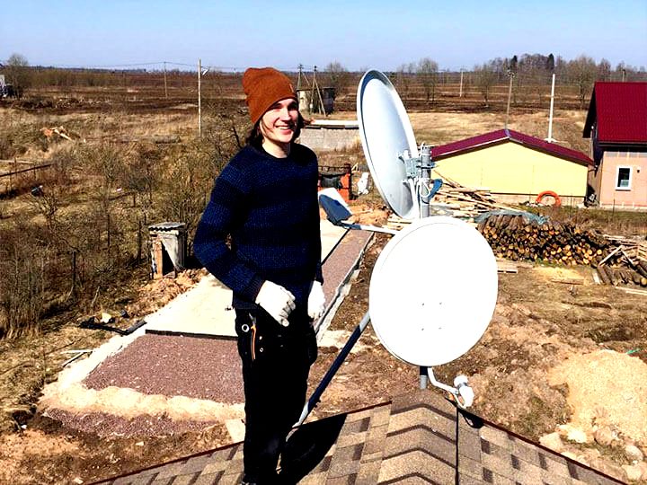 Установщик антенн на крыше дачного домика во время установки оборудования, поселок Рыбачий, новосибирский округ